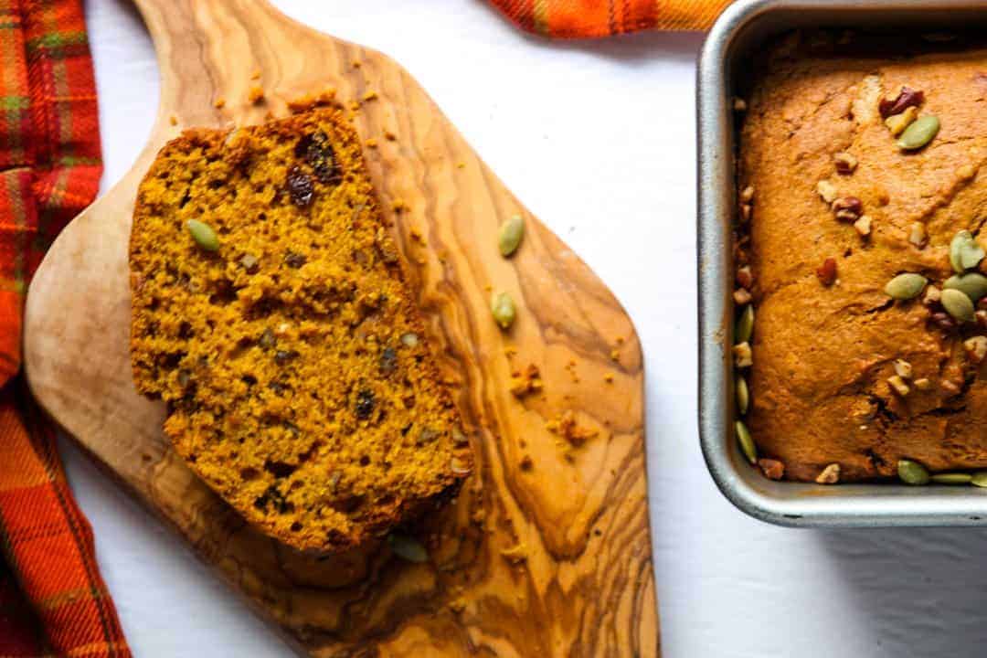 A piece of pumpkin bread on a wooden cutting board